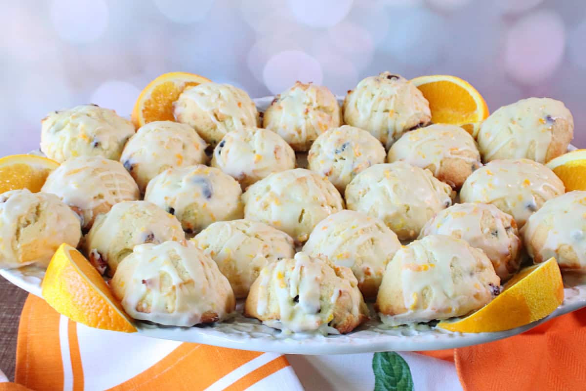A pretty platter full of Orange and Cranberry Ricotta Cookies garnished with glaze.