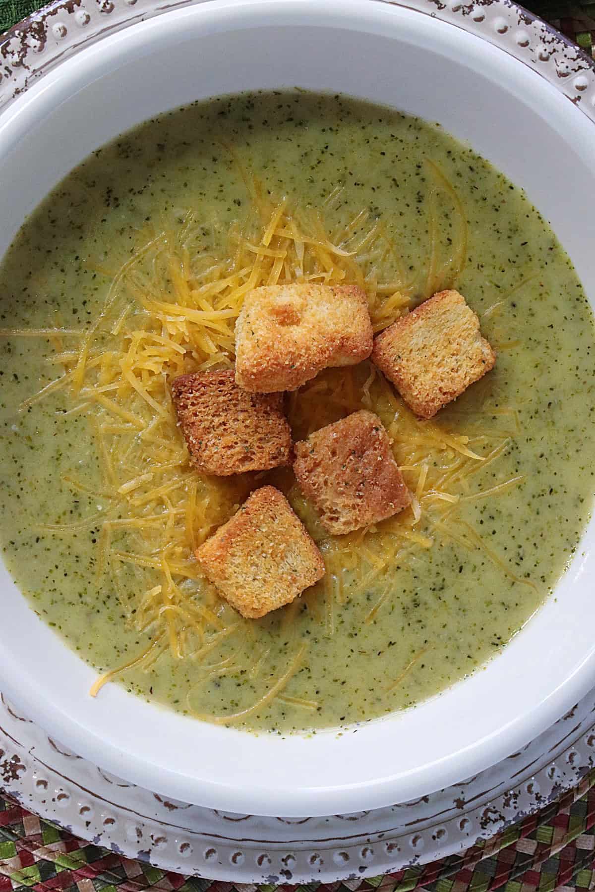 Five croutons, melted cheese, and broccoli cheddar soup in a bowl.