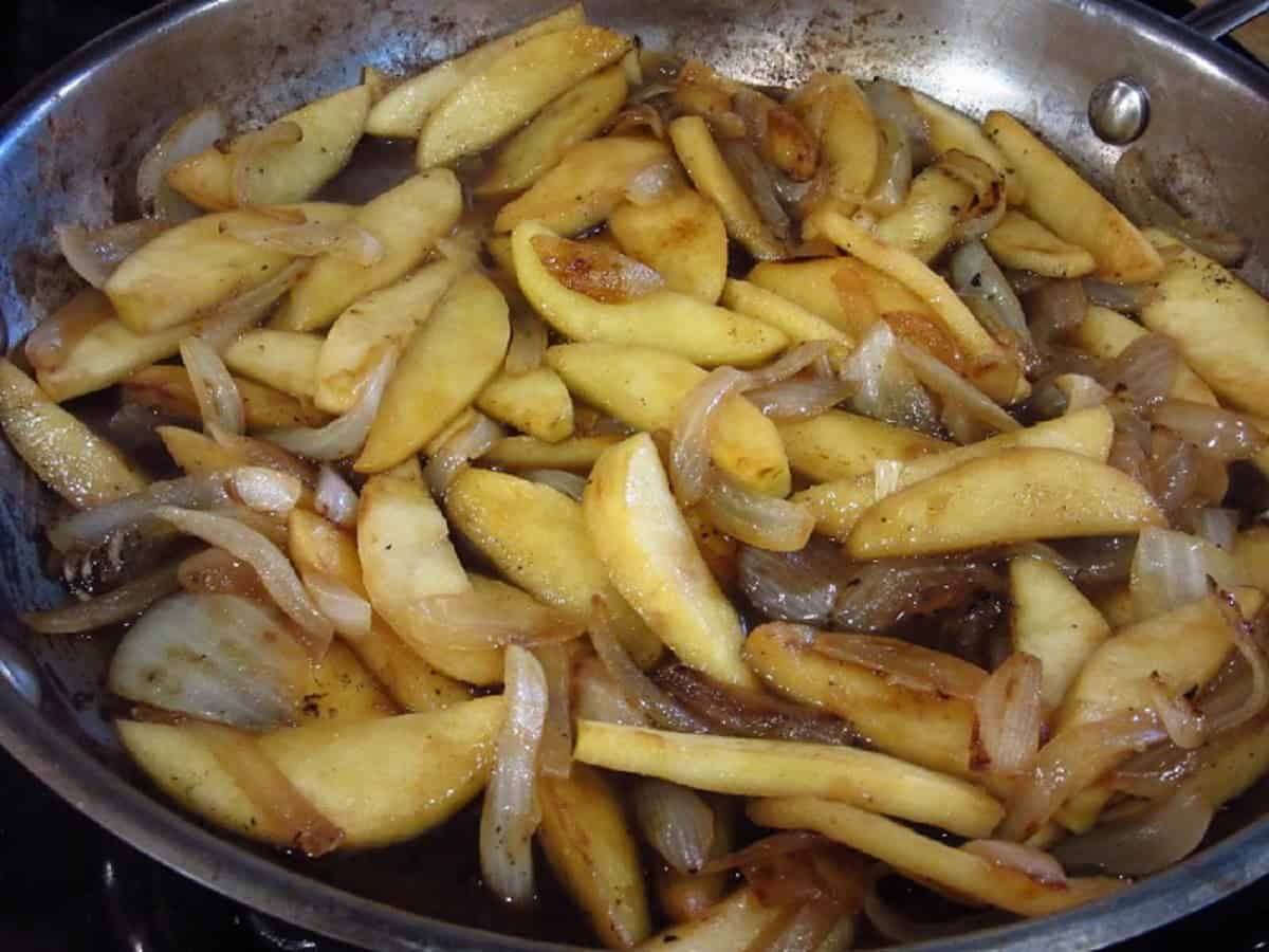 Sauteed apples and onions in a large silver skillet.