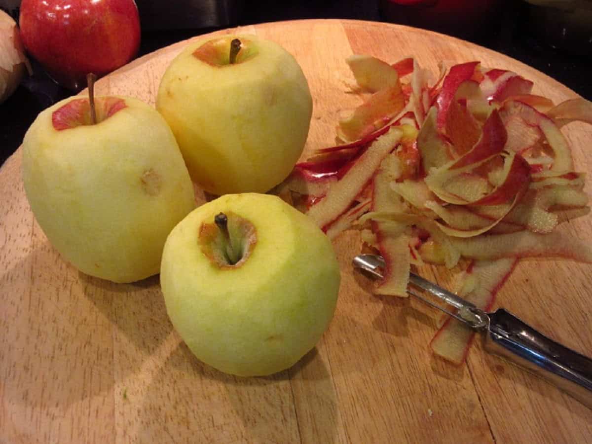 Peeled apples on a wooden cutting board.