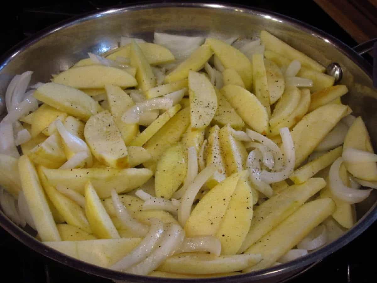 Salt and pepper in a skillet with apple and onion slices.