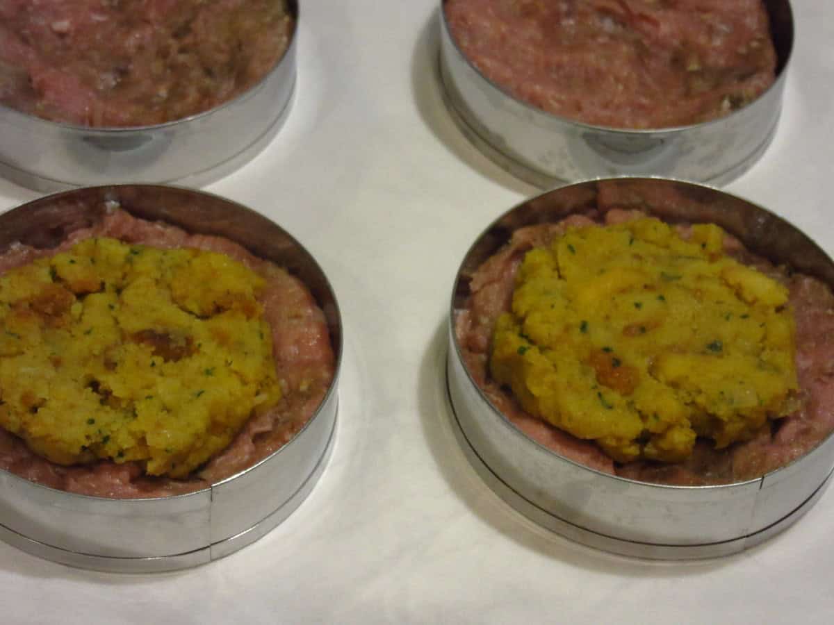 Stuffing and ground turkey inside a ring mold for making stuffed turkey burgers.