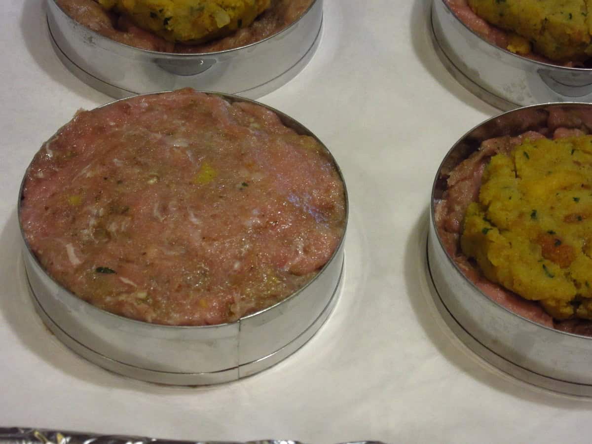 A raw stuffed turkey burger inside a round ring mold.