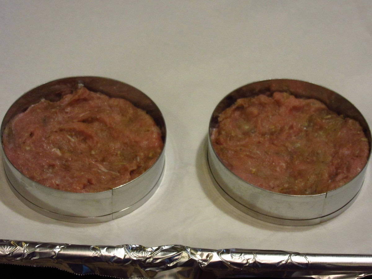 Two round ring molds filled half way full with ground turkey.