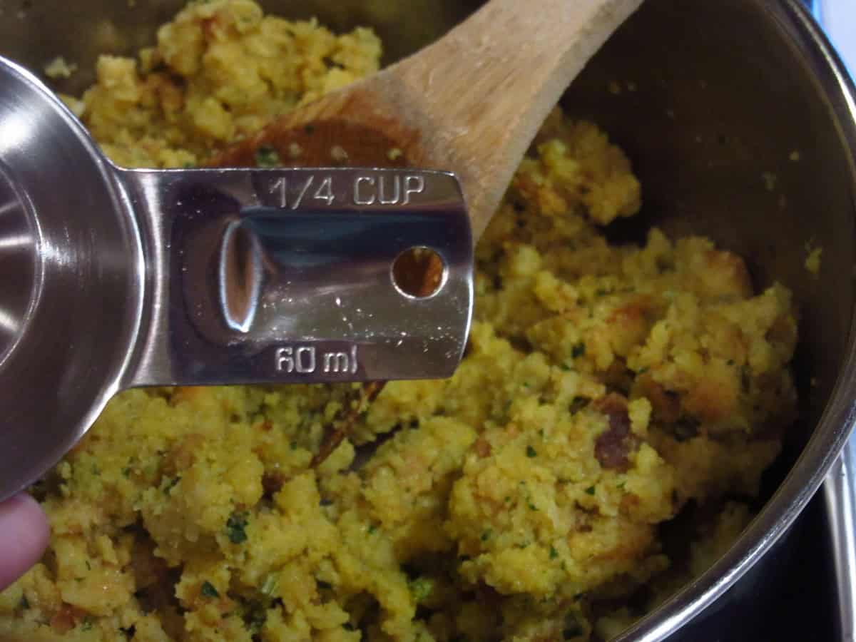 A quarter cup measuring cups over a bowl of stuffing.