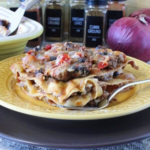 A hearty slice of Mexican Turkey Taco Lasagna on a yellow plate with a fork.