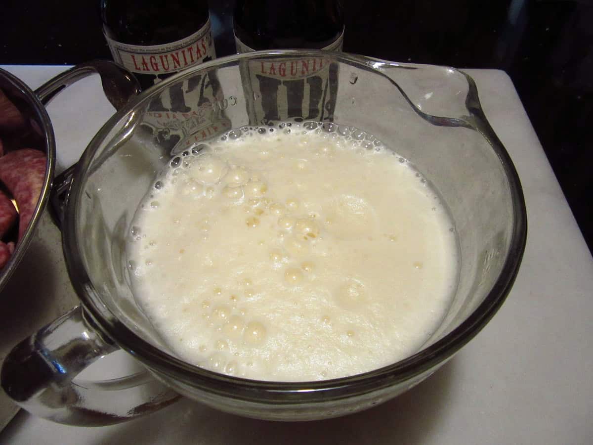Foamy beer in a glass measuring cup.