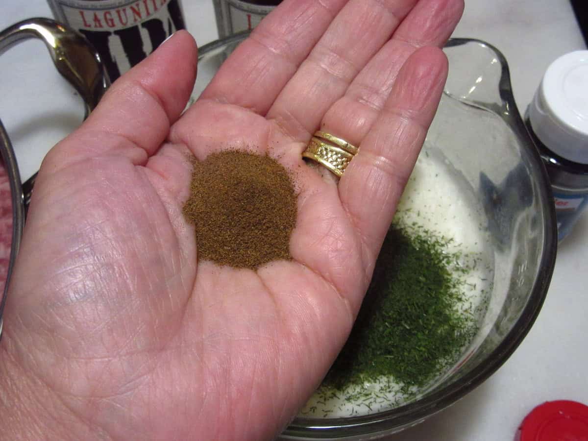 A hand holding a small pile of allspice.