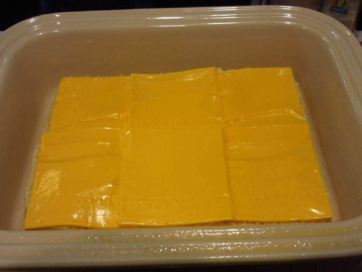 American cheese slices on top of rolls in a casserole dish.