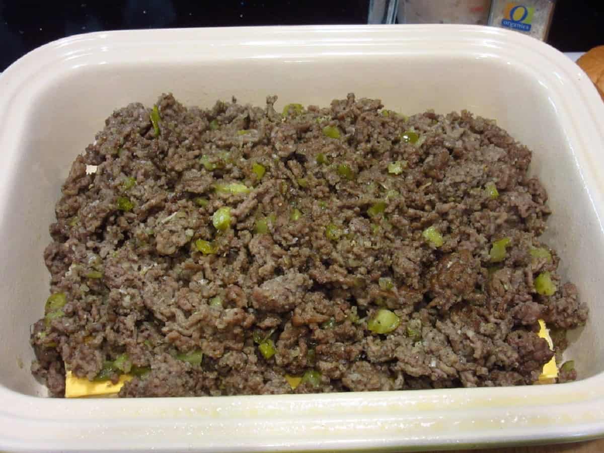 Browned ground beef with pickles in a casserole dish to make big mac sliders.