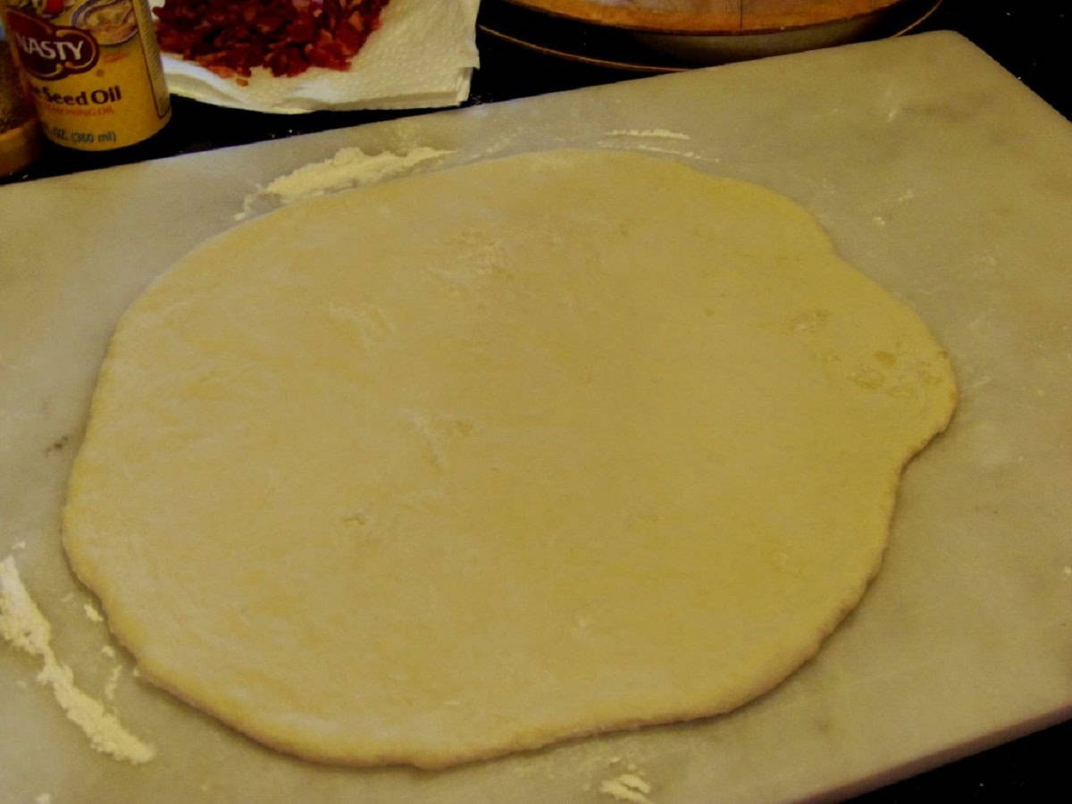A circle of bread dough rolled out on the counter.