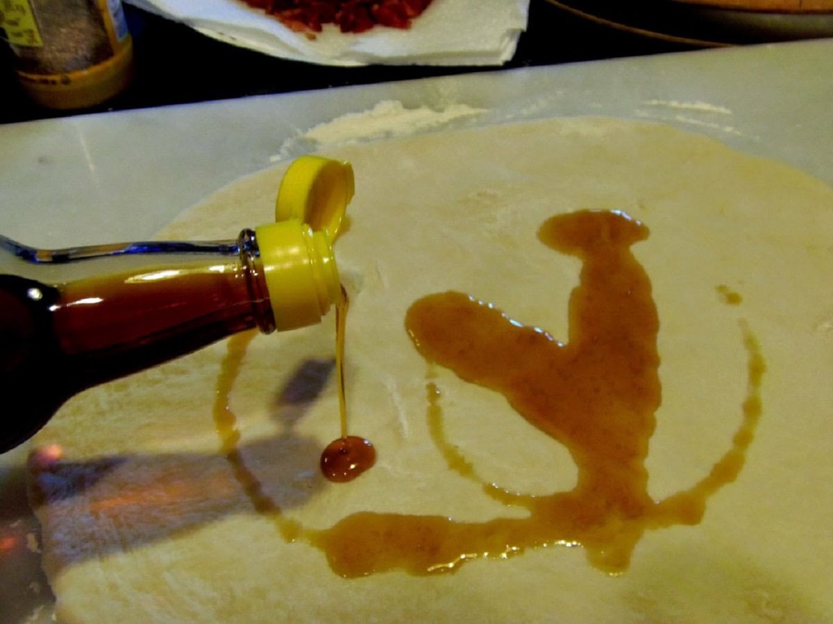 Sesame oil being added to a circle of bread dough.
