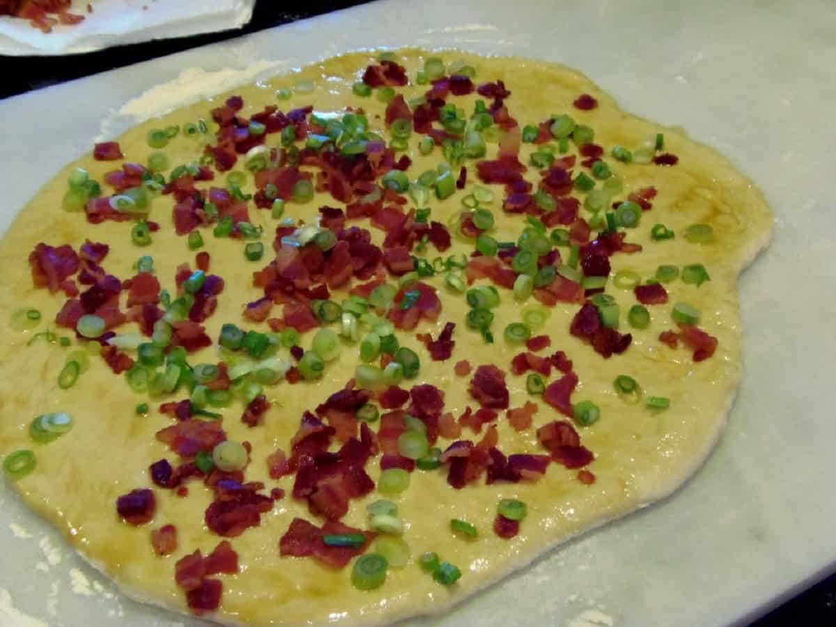 Toppings being added to a bing bread for cooking.