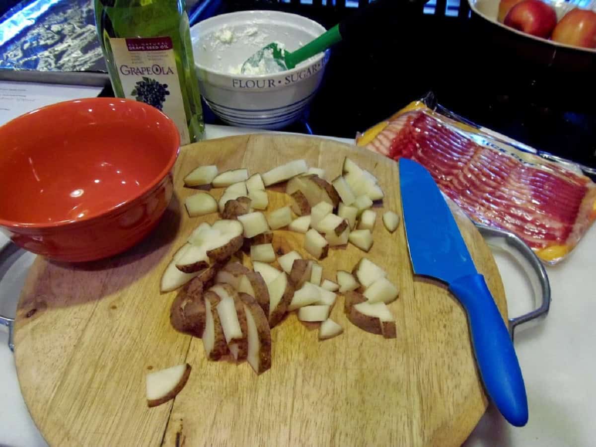 Chopped potatoes and bacon on a cutting board.