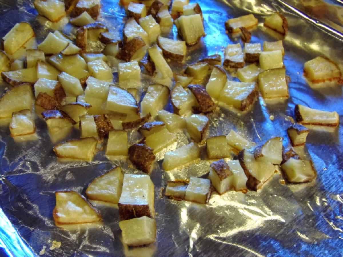 Roasted, chopped potatoes on a foil-lined baking sheet.