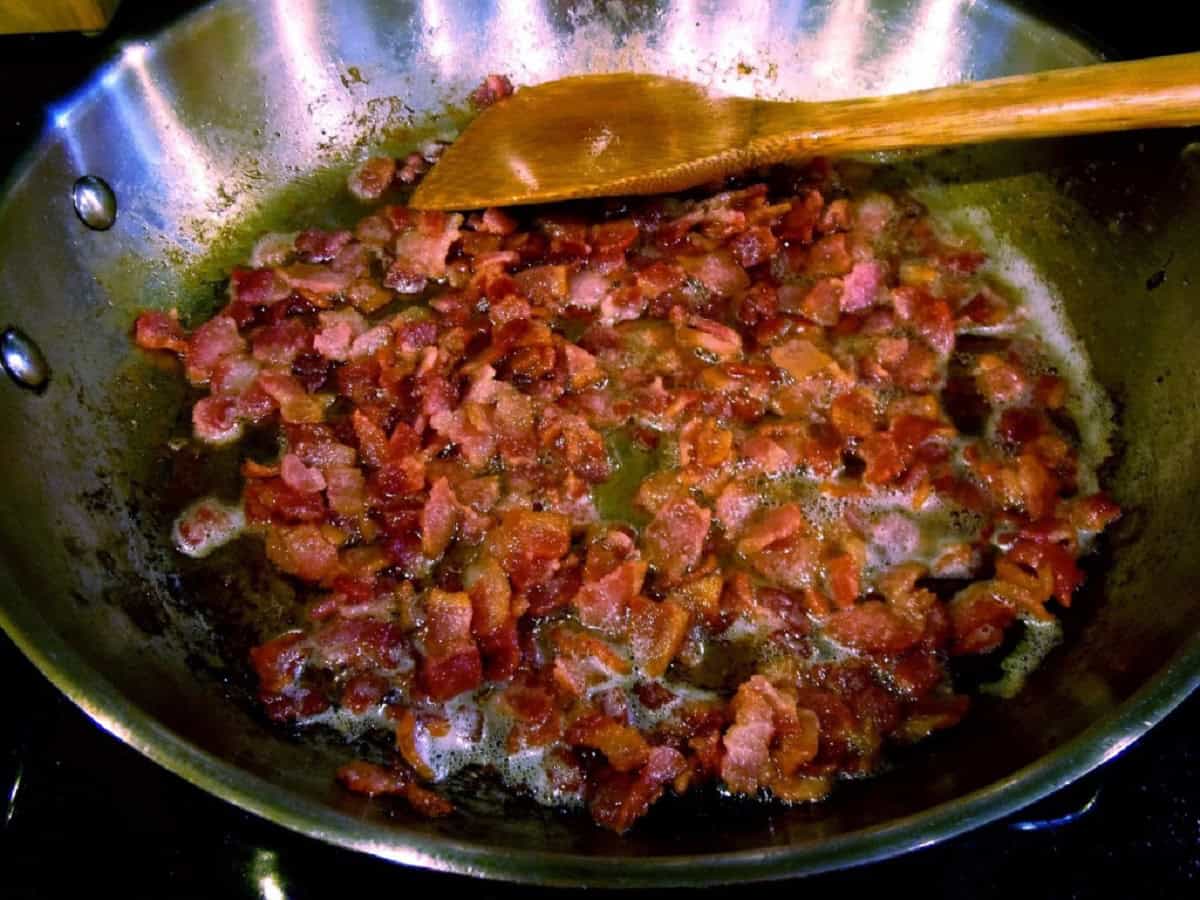 Crispy bacon in a skillet with a wooden spoon.