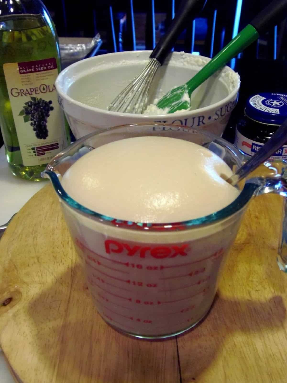 A measuring cup filled with foamy yeast.