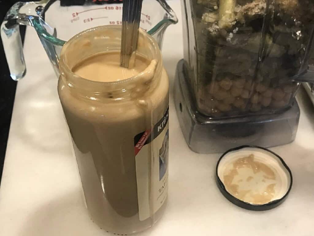 A jar of tahini with a spoon.