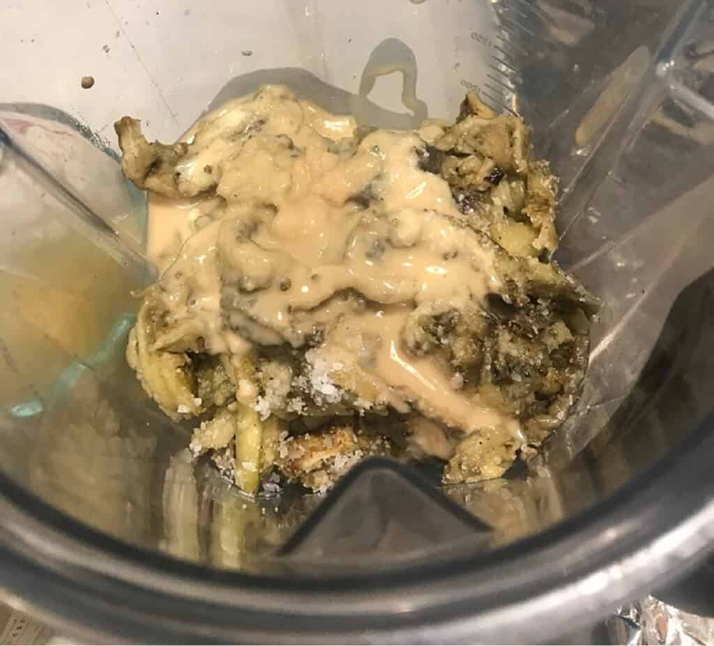 Tahini inside a blender with eggplant to make hummus.