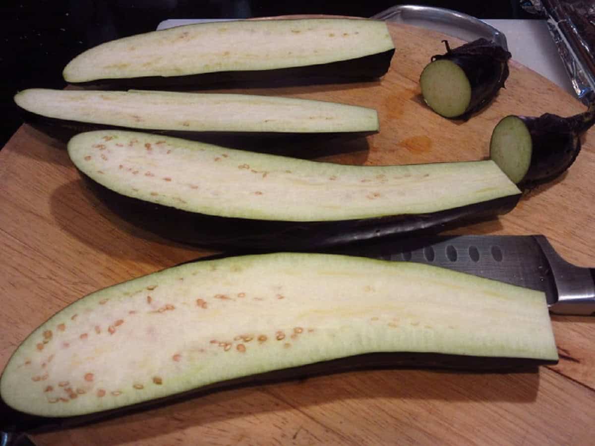 Sliced eggplants on a cutting board with a knife.