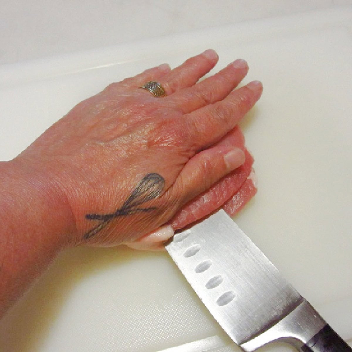 A flat hand on a pork chop while slicing the chop in half.