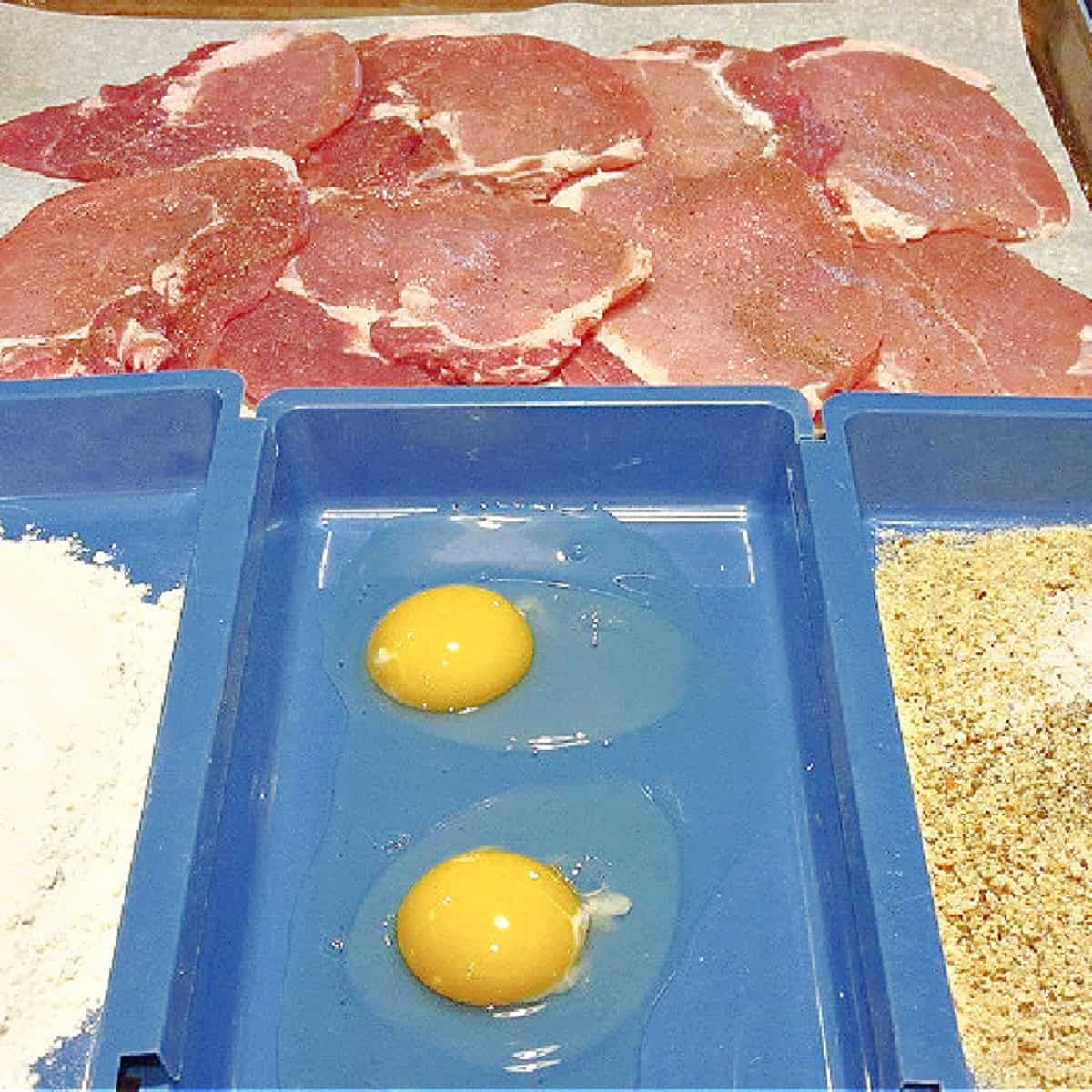 A breading station with flattened pork cutlets in the background.