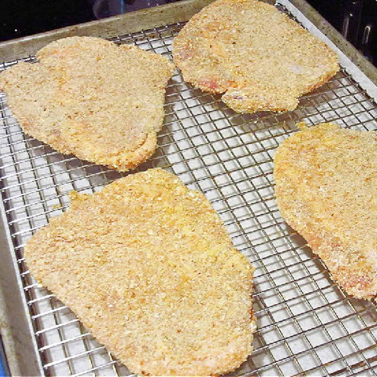 Breaded pork cutlets on a wire rack.