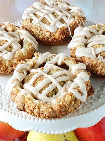 Apple blossoms drizzled with vanilla glaze on a cake stand.