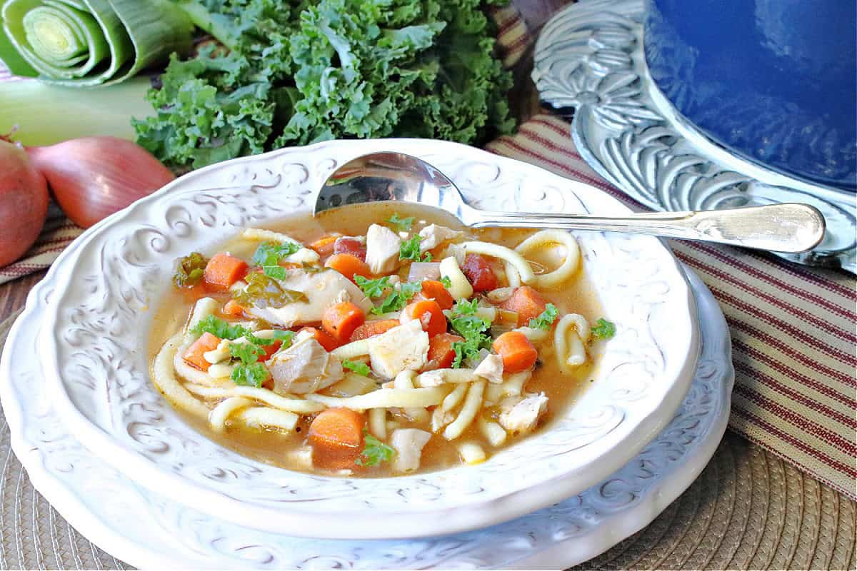 Kale and carrots inside a bowl of Chicken Noodle Soup with Leeks and Kale.