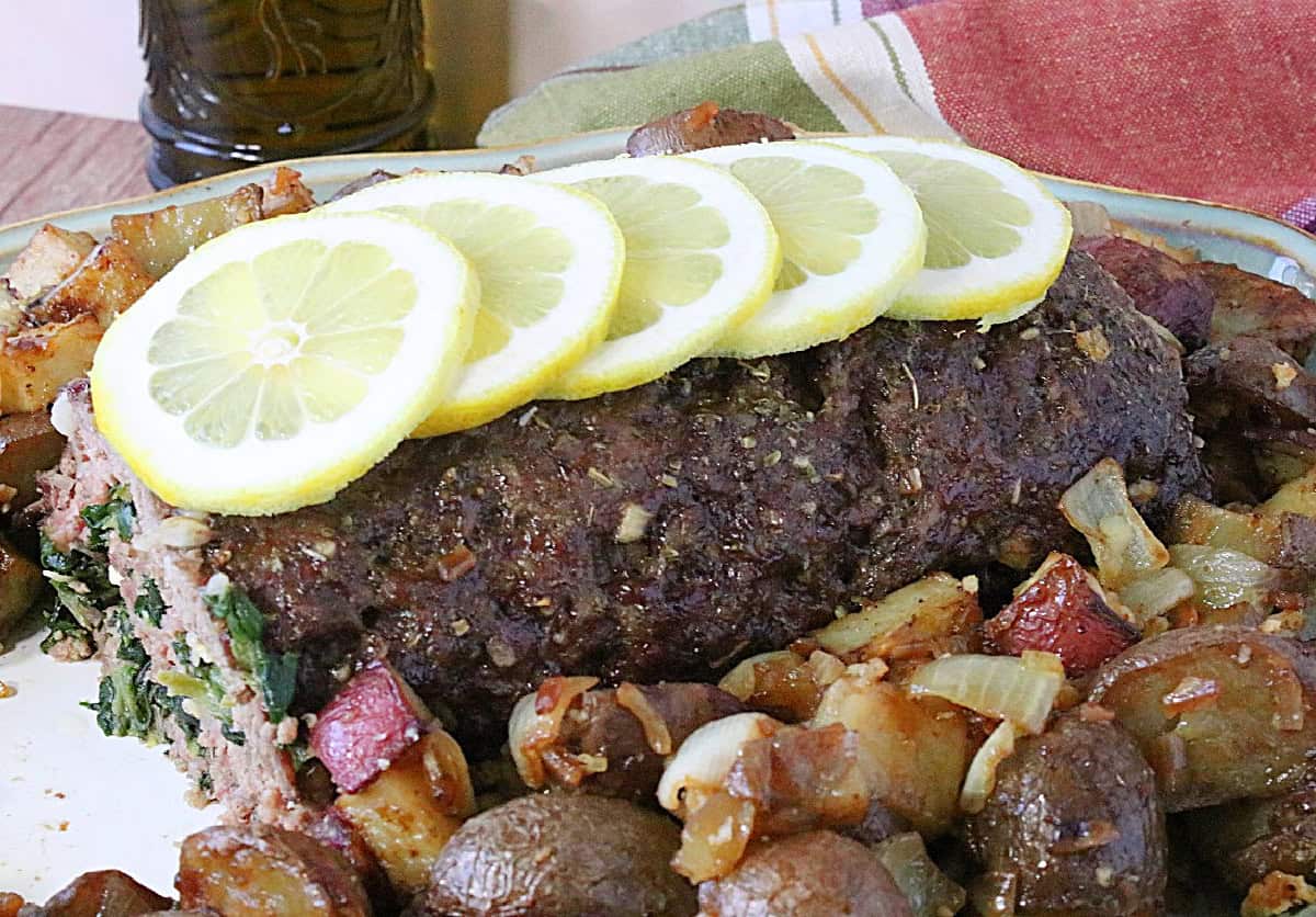 A rolled Greek meatloaf lined with lemon slices along the top.