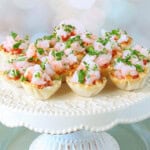 Elegant looking Shrimp Cocktail Appetizer Bites on a white cake stand.