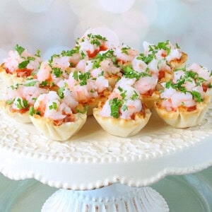 Elegant looking Shrimp Cocktail Appetizer Bites on a white cake stand.