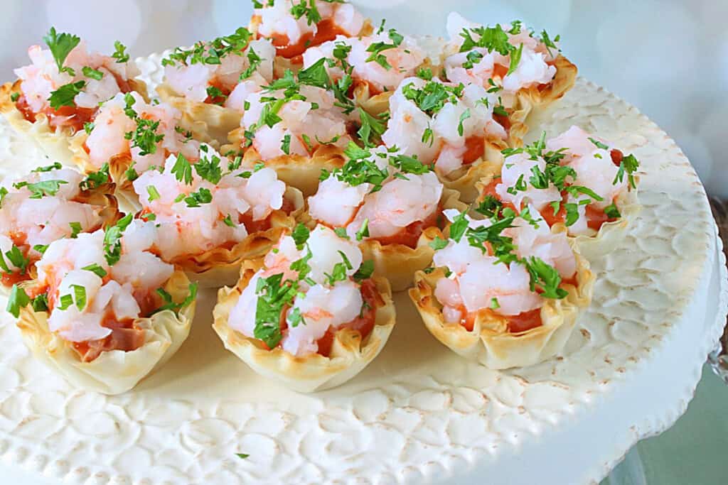 Diced shrimp with cocktail sauce and parsley in phyllo appetizer shells.
