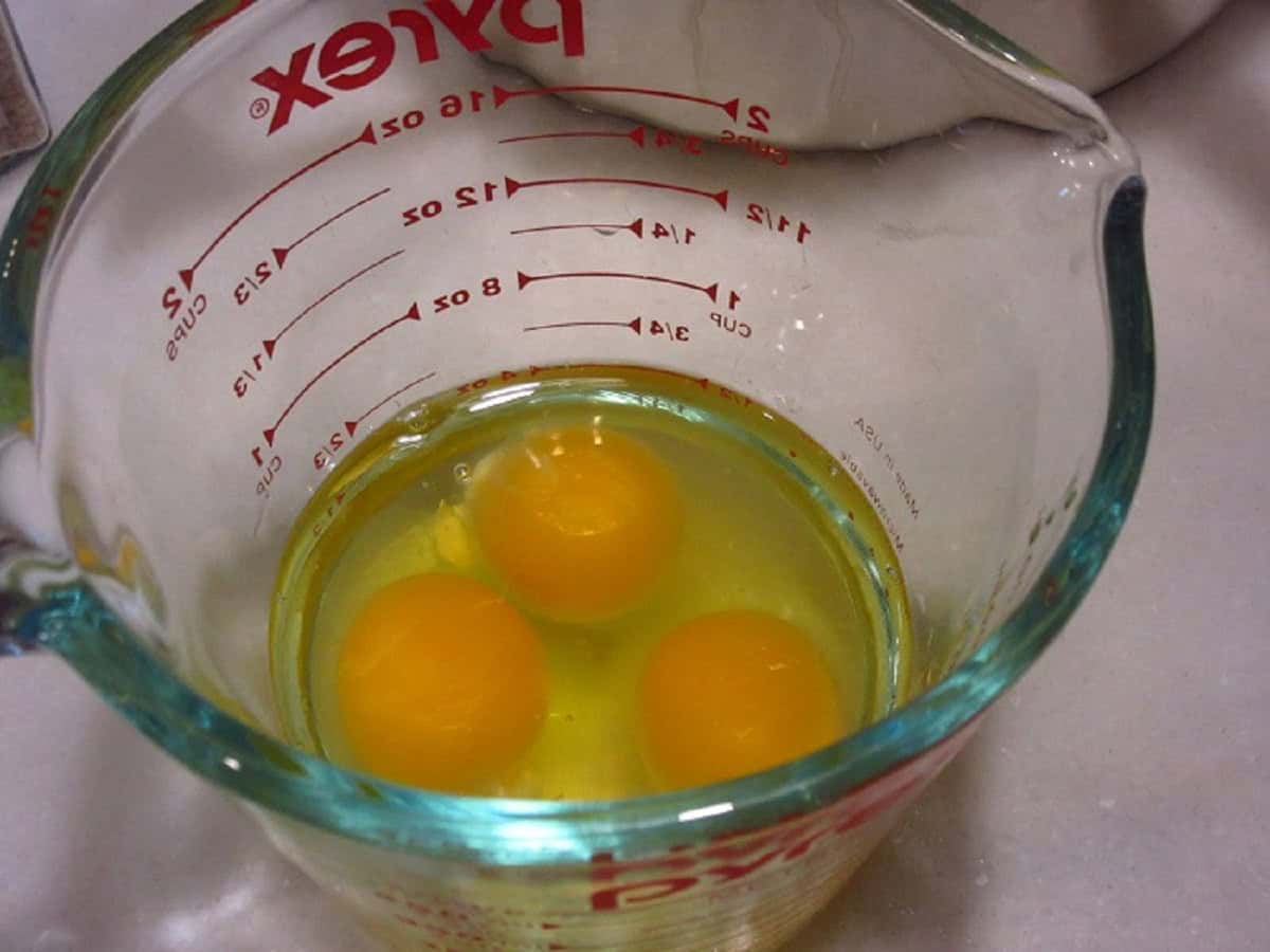 Three eggs in a glass measuring cup.