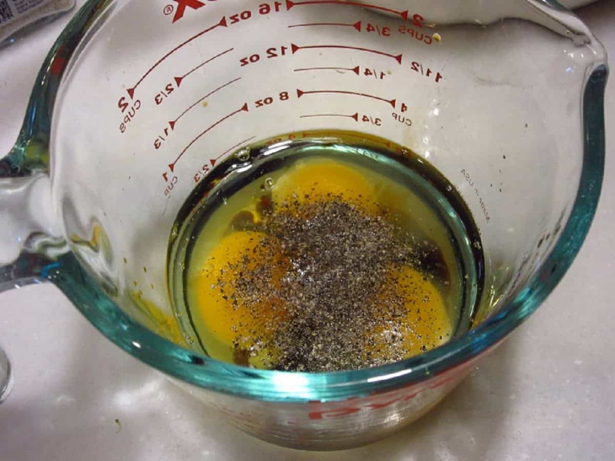 Eggs, salt and pepper in a glass measuring cup.