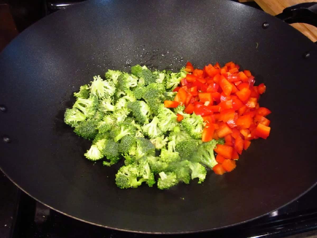 Chopped broccoli and red peppers in a wok.