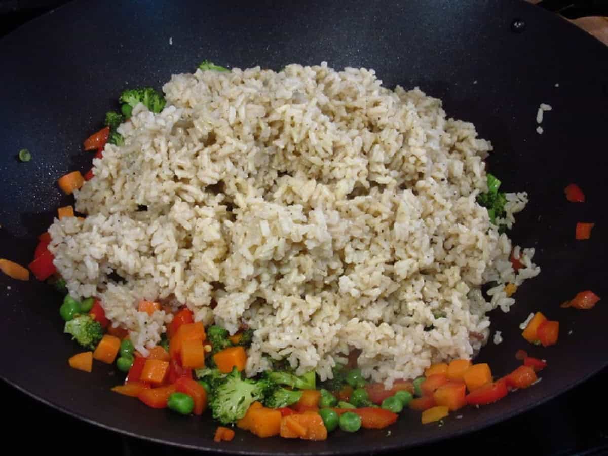 Stir-fried brown rice ingredients in a wok.
