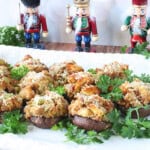 Stuffed cremini mushroom caps on a white platter surrounded by pasrley.