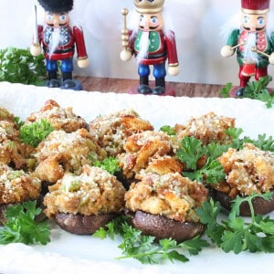 Stuffed cremini mushroom caps on a white platter surrounded by pasrley.