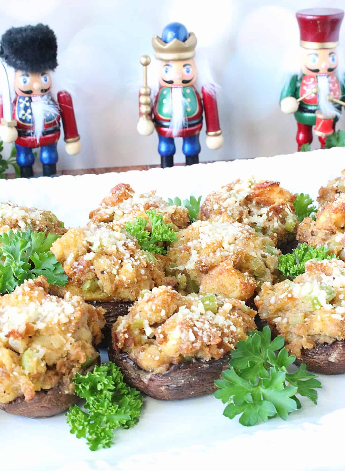 Three small nutcrackers behind a platter of stuffing stuffed mushrooms.