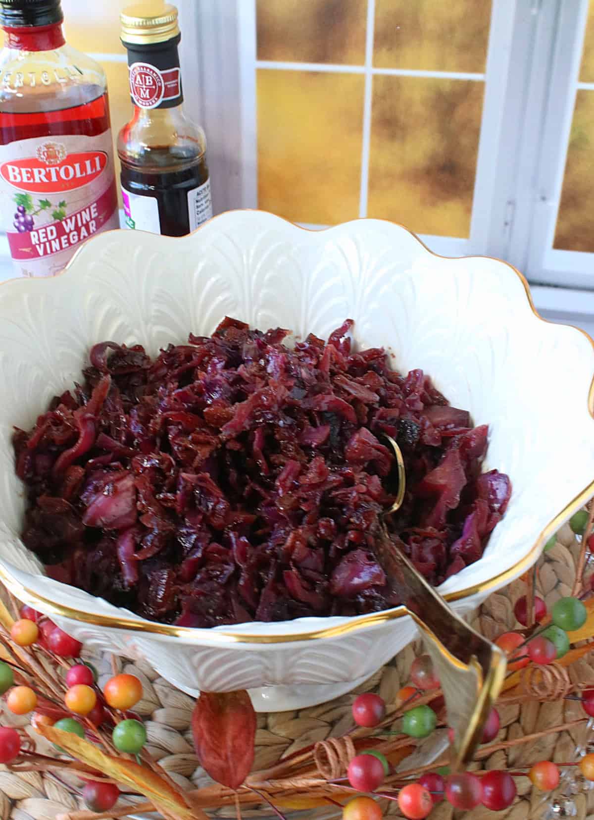 A pretty white bowl filled with Sweet and Sour Red Cabbage along with a golden spoon.