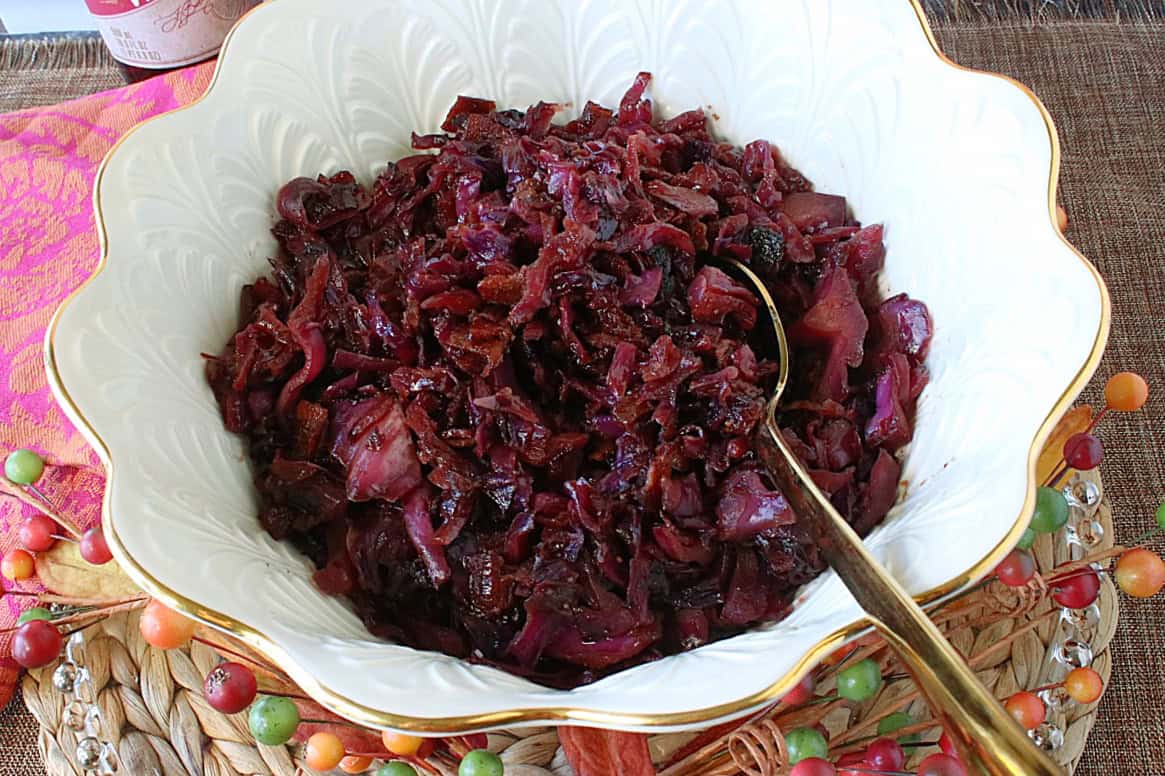 A gold-rimmed, white bowl filled with Sweet and Sour Red Cabbage with bacon.