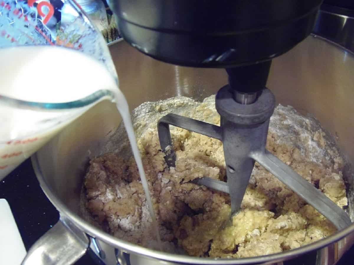 Milke being added to a stand mixer to make a cupcake batter.