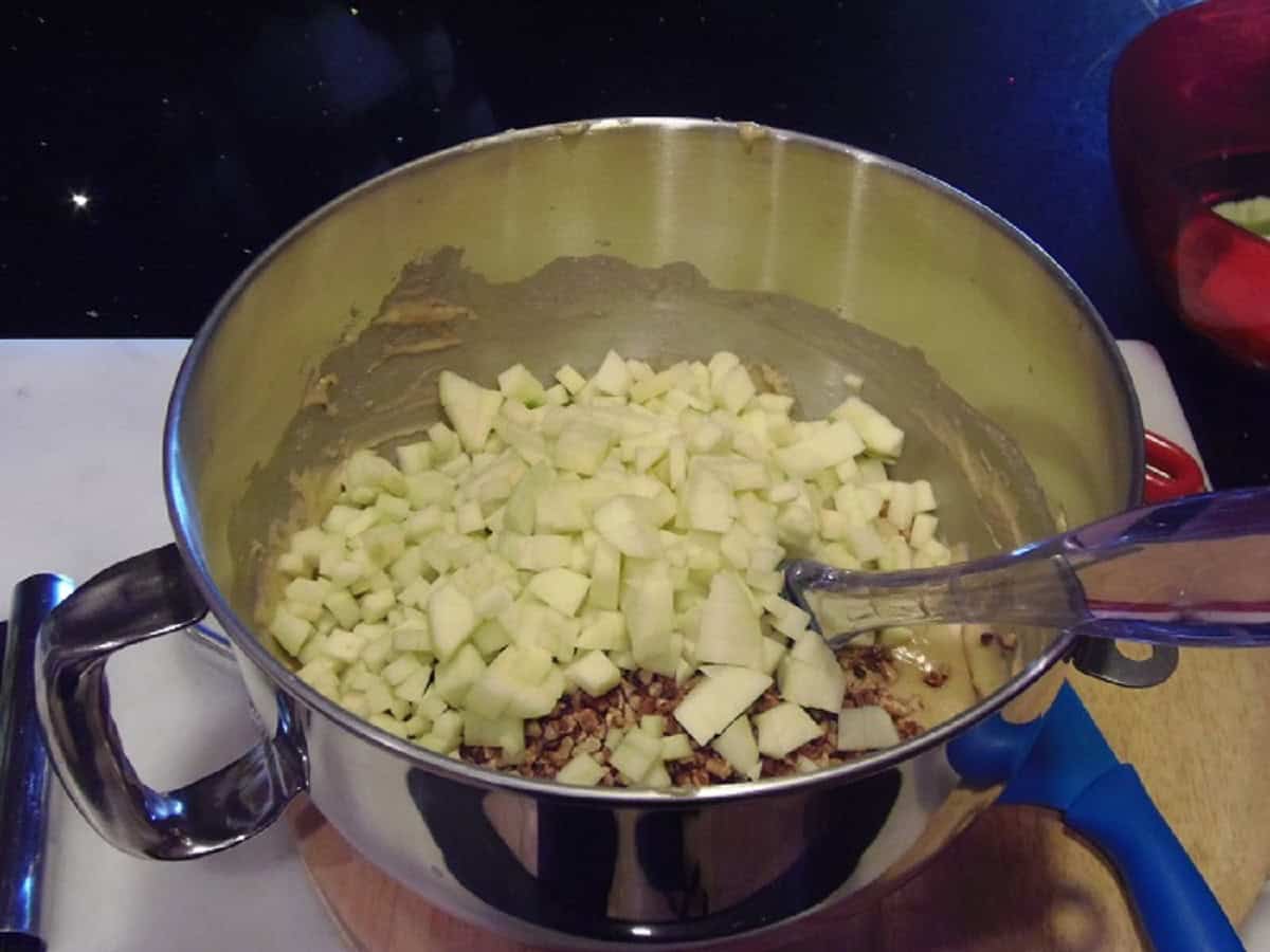 Diced apples added to a bowl of cupcake batter.