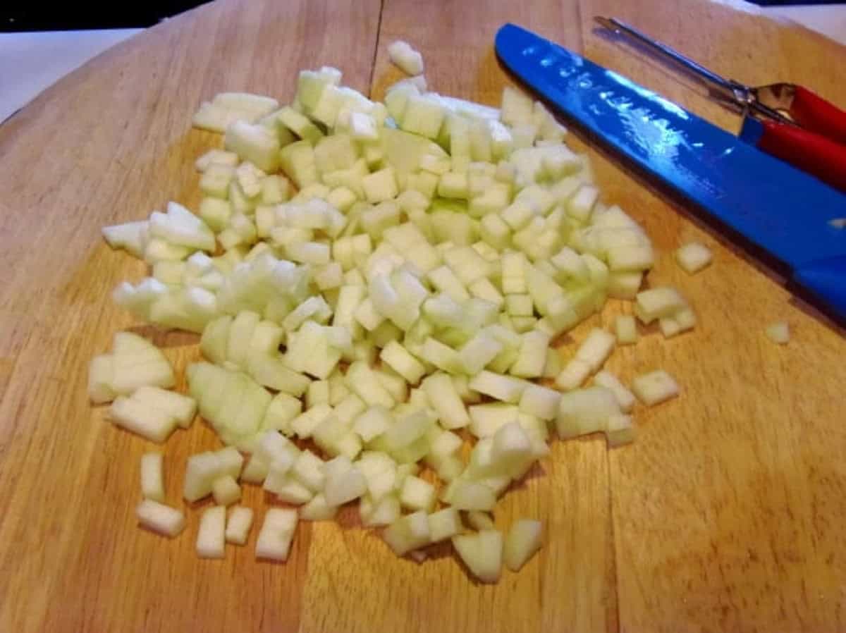Finely diced apples on a wooden cutting board.