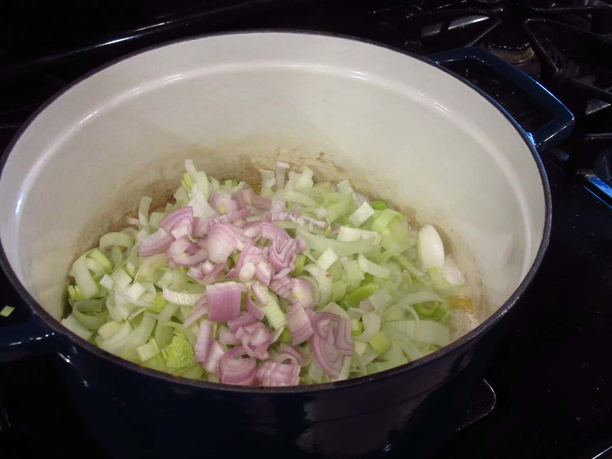Chopped leeks and shallots in a large Dutch oven on the stovetop.