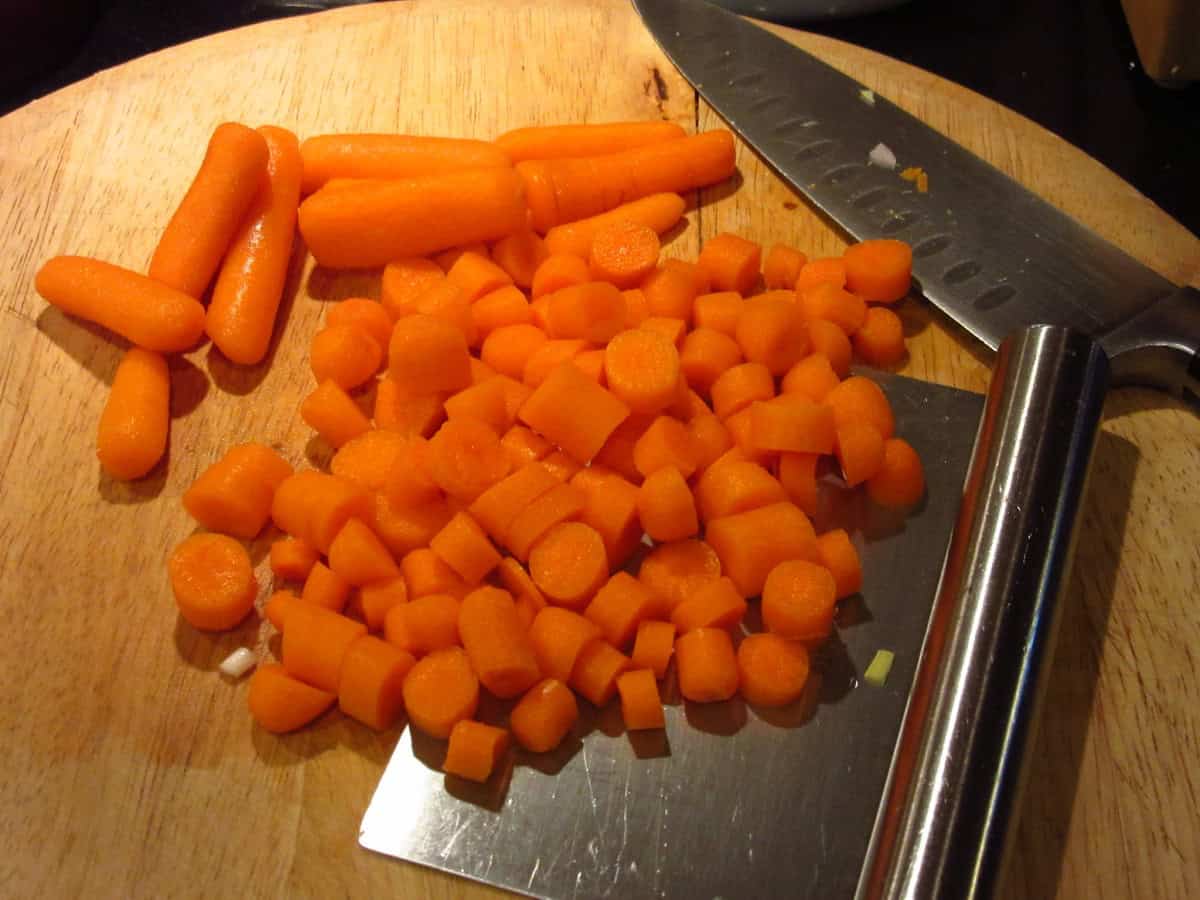 Chopped carrots on a wooden cutting board.