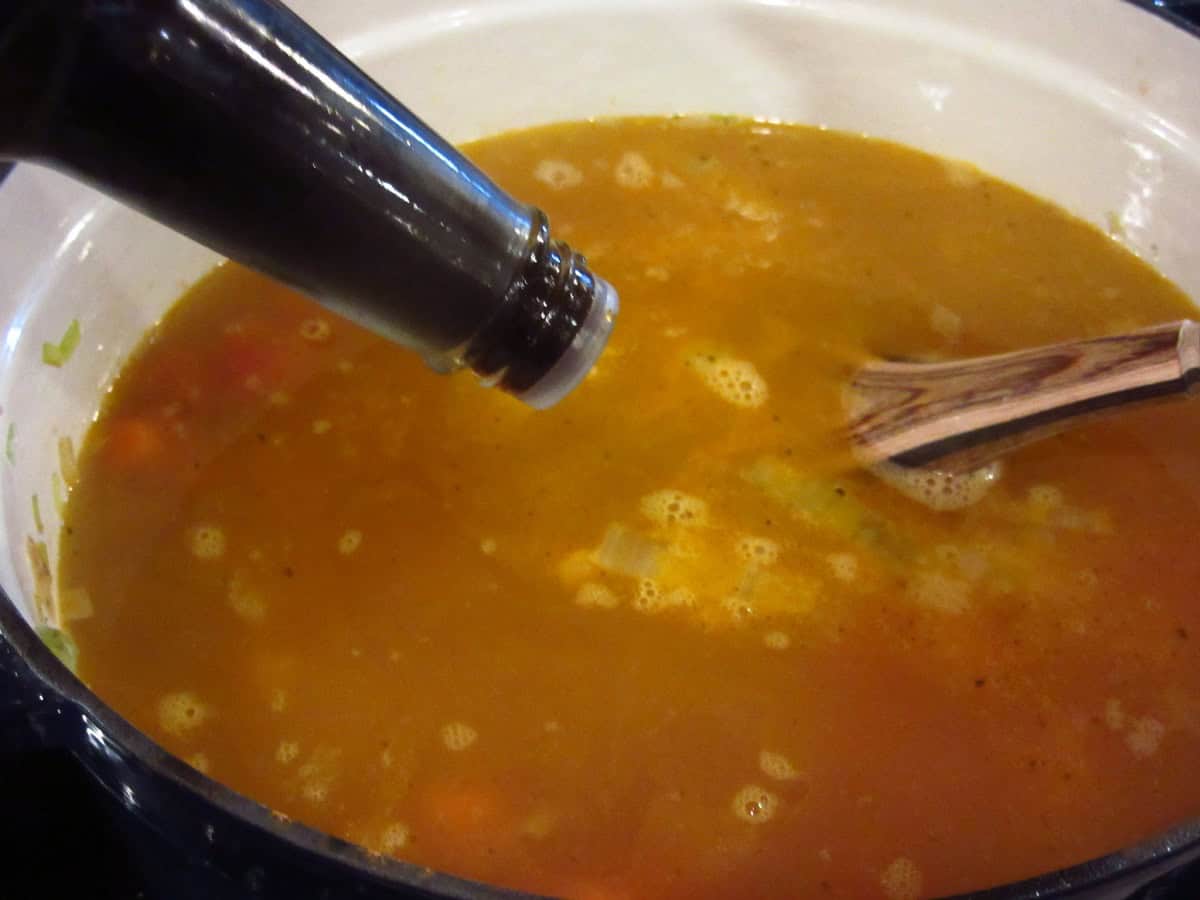 Worcestershire sauce being added to a soup broth.