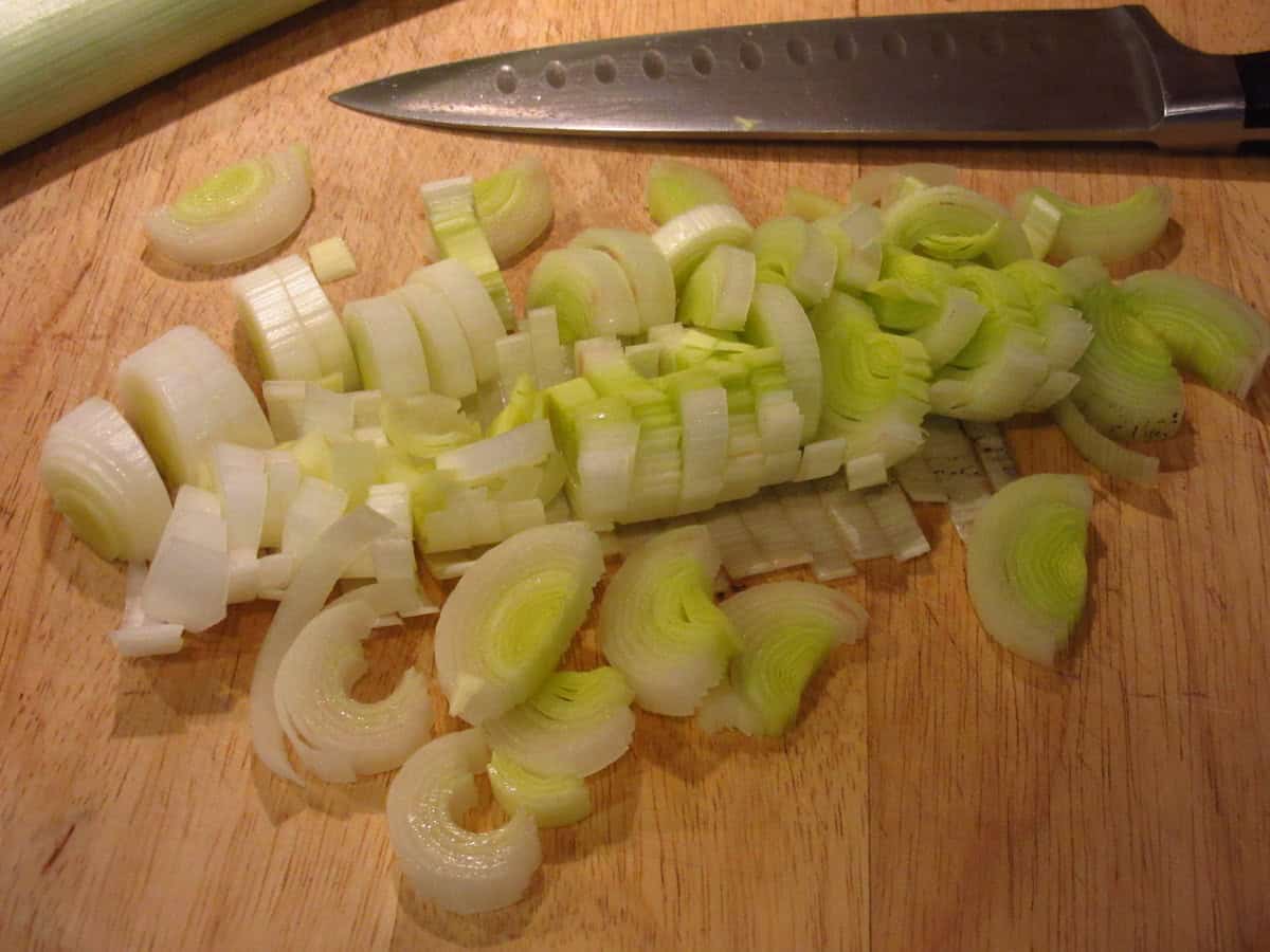 Slices of raw leek on a cutting board.
