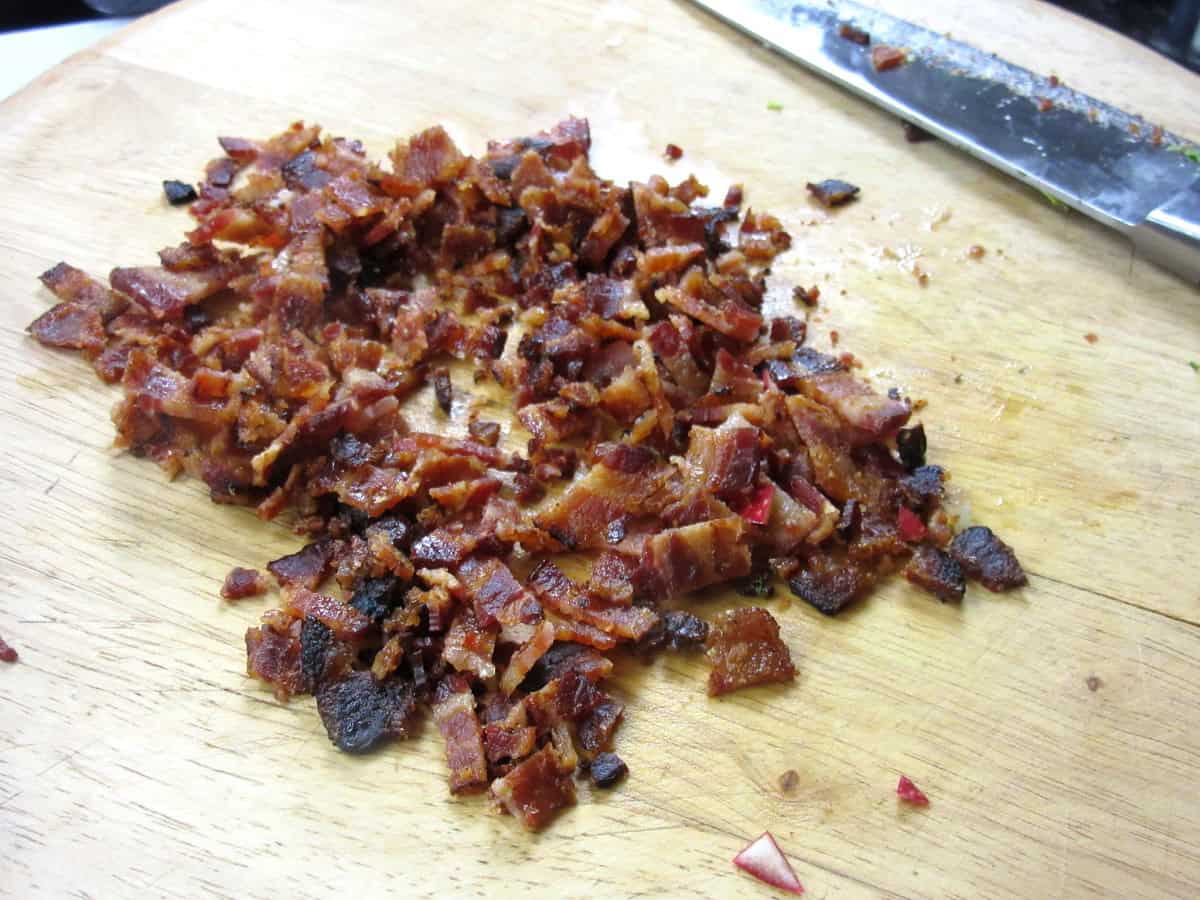 Cooked and chopped bacon on a cutting board.